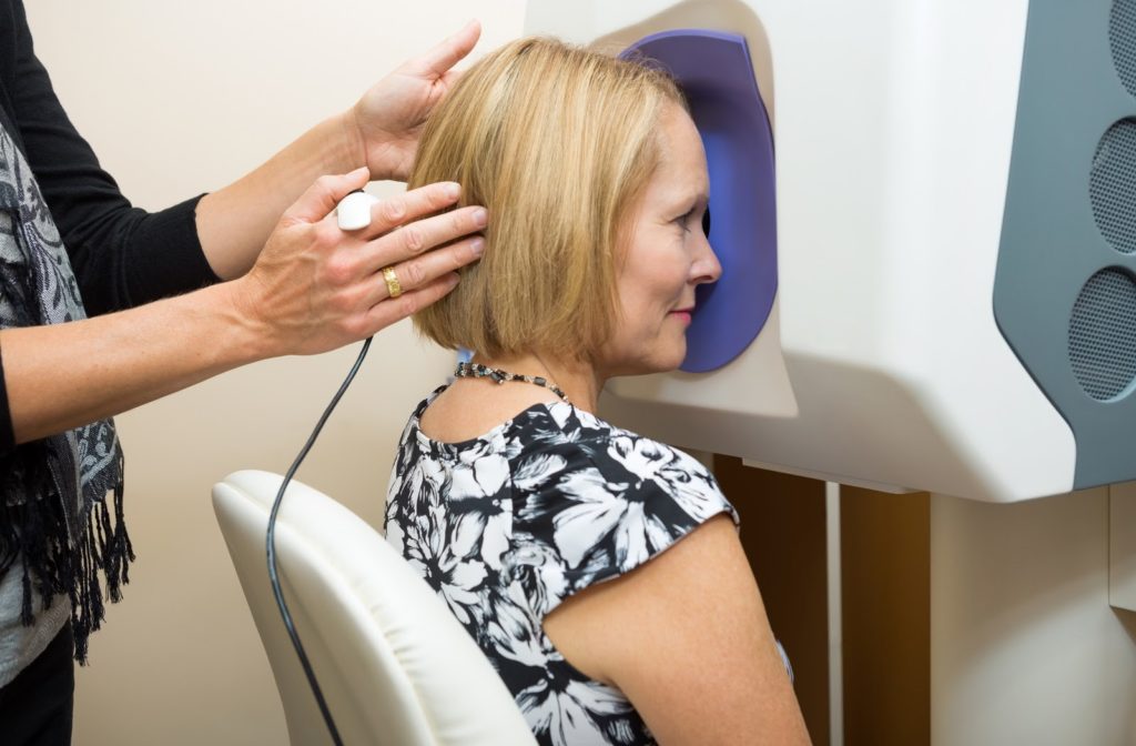 Optometrist adjusting patient's head in front of machine before her retinal checkup.