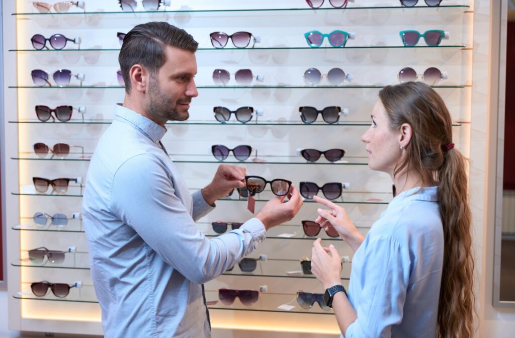 An eye doctor helps a patient select sunglasses with UV protection.