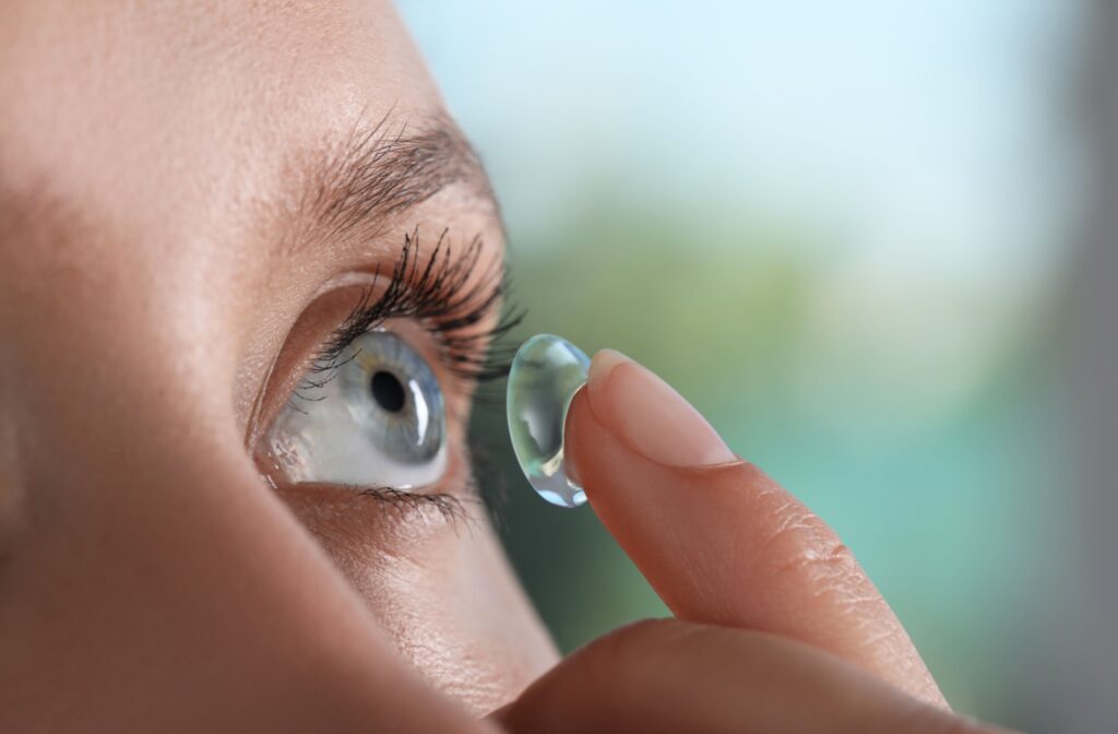 A close up of a contact lens on a finger tip, about to be inserted into an eye