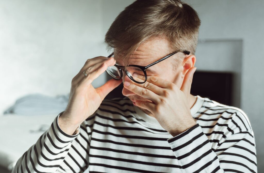 A man rubbing his eyes under his glasses due to dry eye symptoms affecting the comfort of his vision.