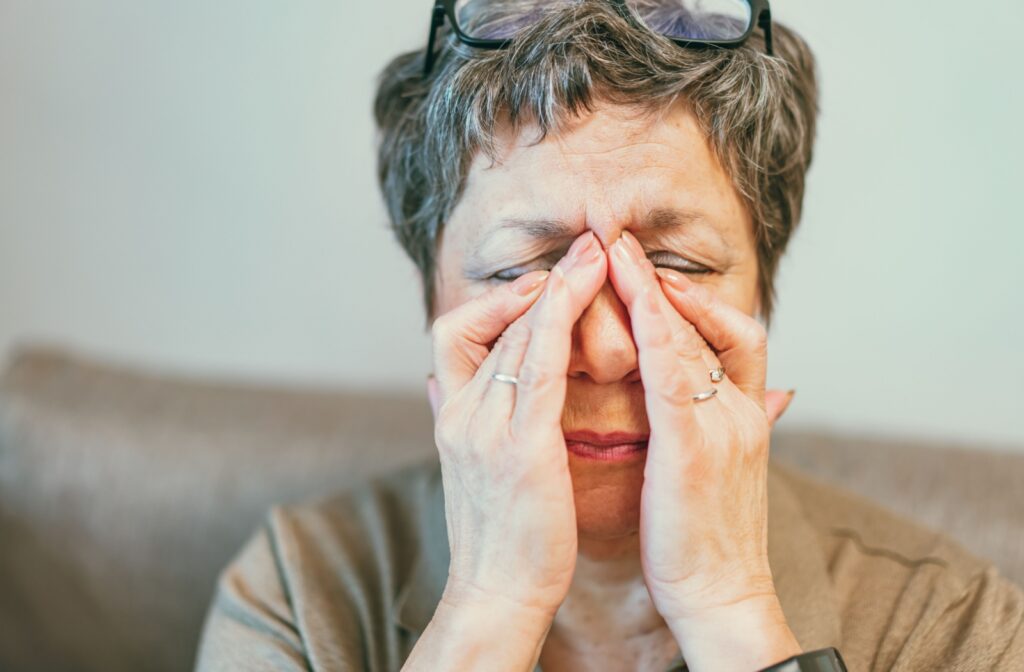 A person rubbing their eyes with their glasses on their head, experiencing a bit of dizziness from new eyewear.
