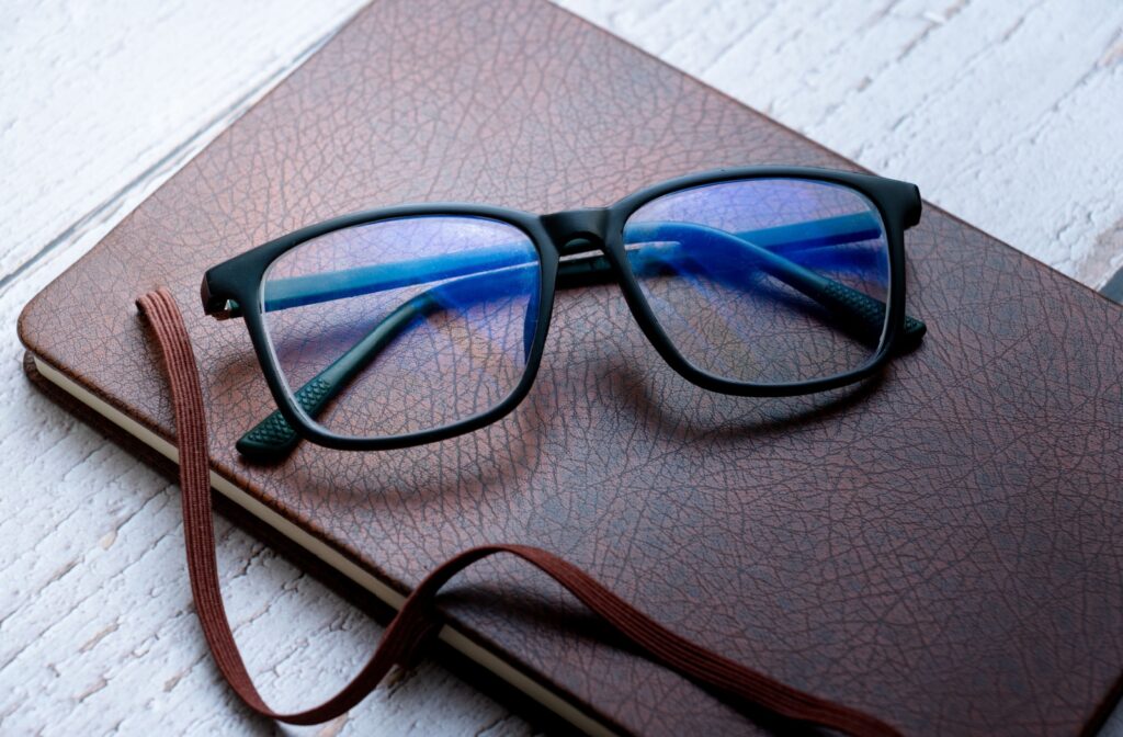 A pair of glasses with anti-reflective coating, sitting on a notebook.